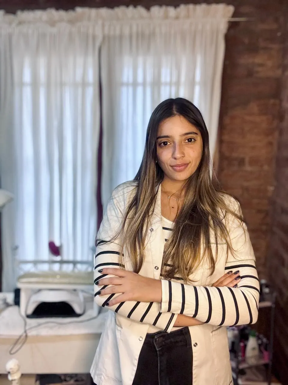 Paula Tazzioli con ambo blanco, de brazos cruzados, en su espacio de trabajo